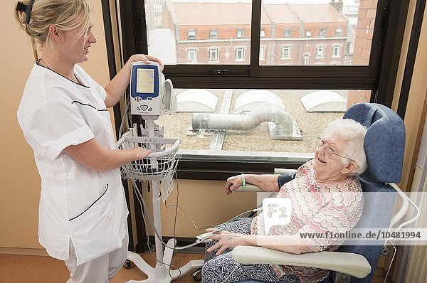 Reportage in the Geriatrics service in Saint-Vincent de Paul hospital in Lille  France. A nurse checks a patient´s blood pressure in her hospital room.