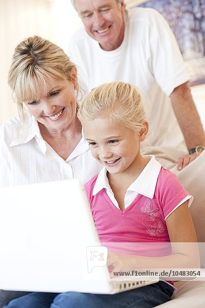 MODEL RELEASED. Grandparents and granddaughter using a laptop. Grandparents and granddaughter