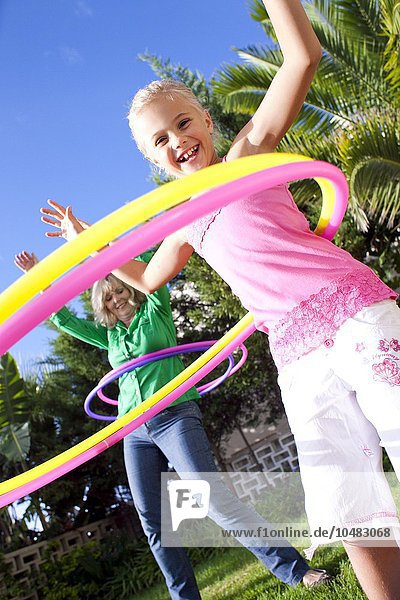 MODEL RELEASED. Hula-hooping. Grandmother and granddaughter hula-hooping. Hula-hooping