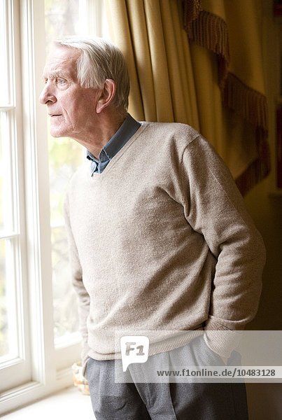 EIGENSCHAFT FREIGEGEBEN. MODELL FREIGEGEBEN. Einsamer älterer Mann schaut aus dem Fenster Einsamer älterer Mann