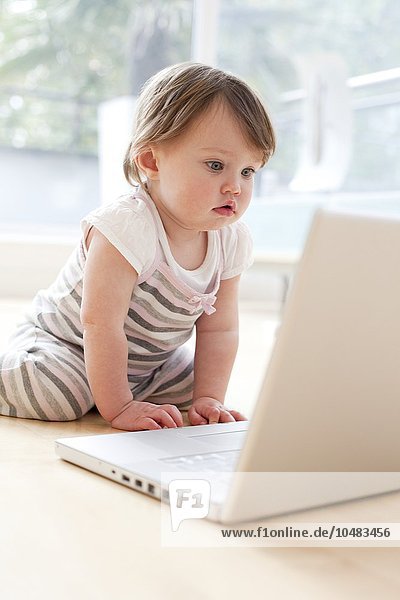 MODEL RELEASED. Baby playing with a laptop. 15 month old girl looking at a laptop. Baby playing with a laptop