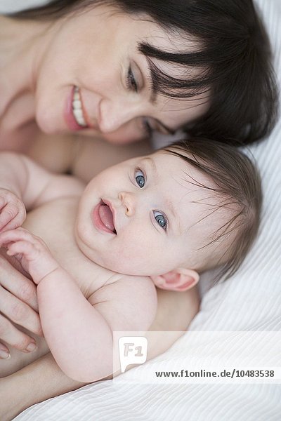 MODEL RELEASED. Mother and baby. Mother cuddling her 7 week old daughter. Mother and baby