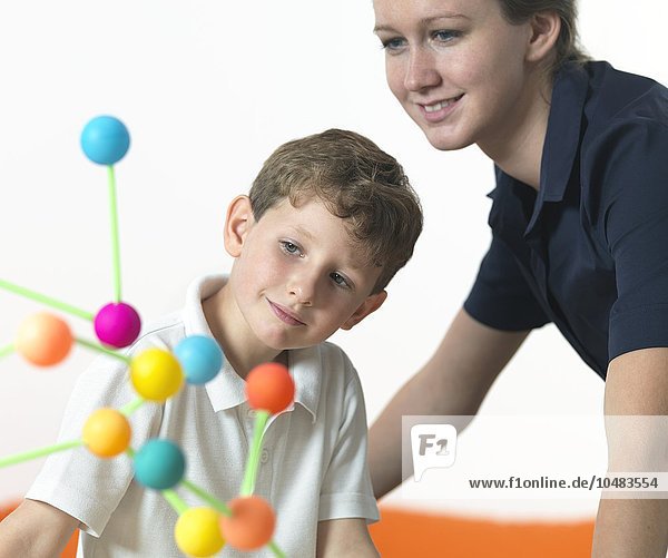 MODELL FREIGEGEBEN. Chemieunterricht. 6-jähriger Junge und sein Lehrer betrachten eine Molekularstruktur Chemieunterricht
