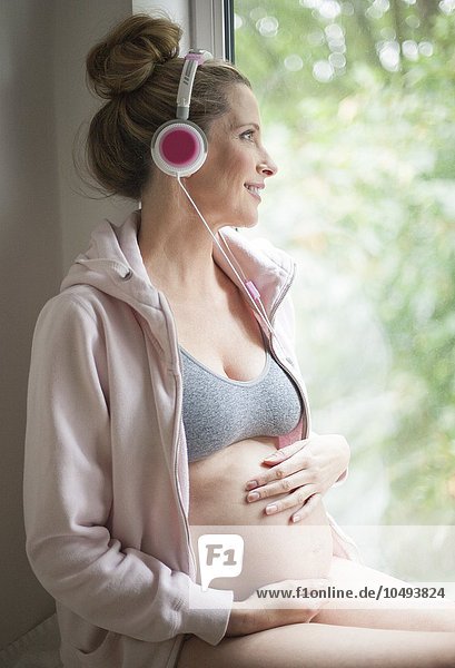 MODEL RELEASED. Pregnant woman listening to music. Pregnant woman listening to music