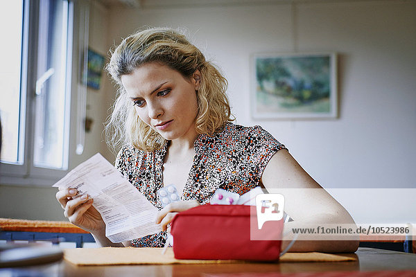 Frau liest Beipackzettel für Medikamente.