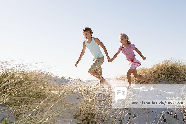 Boy and girl running on sand dune
