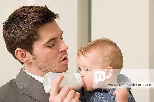 Businessman giving bottle to baby