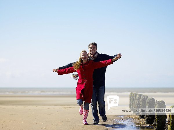 Young couple skipping on the beach