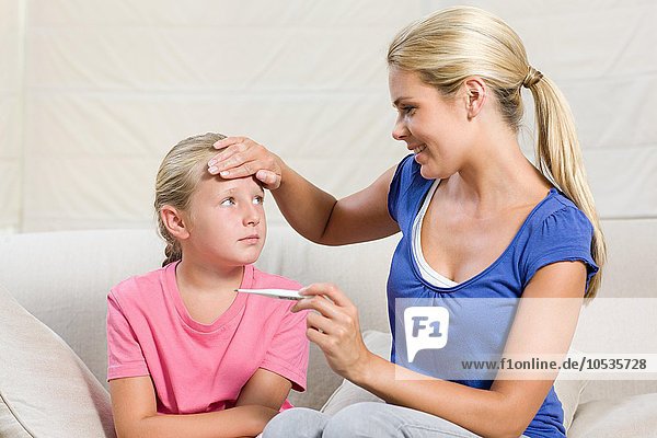 Krankes Mädchen und Mutter mit Thermometer