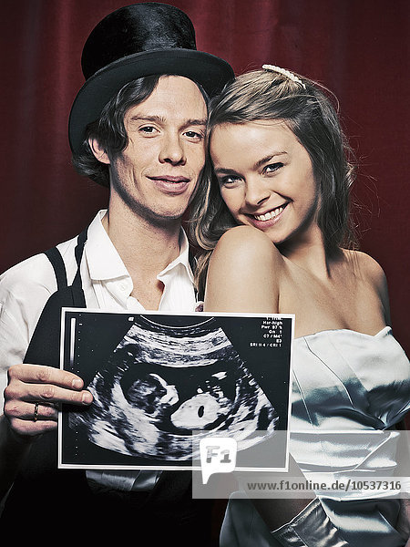 Newlywed couple holding sonogram