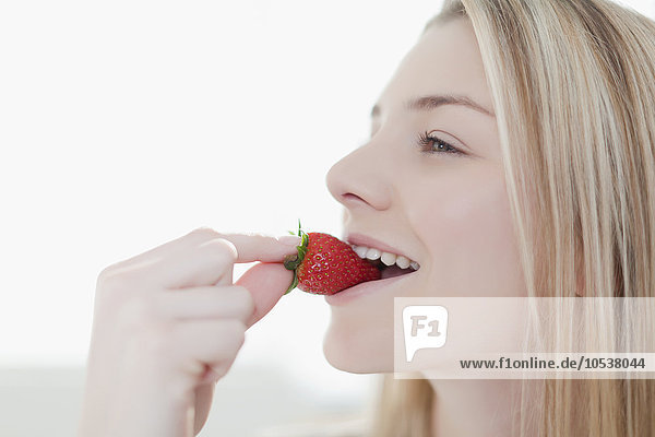 Lächelnde Frau isst Erdbeere