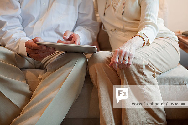 Seniorenpaar mit Computertablett zu Hause  Mittelteil