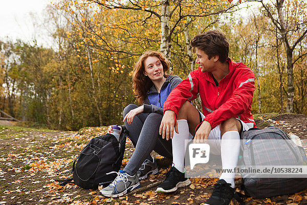 Junges Paar in Sportbekleidung im Wald sitzend