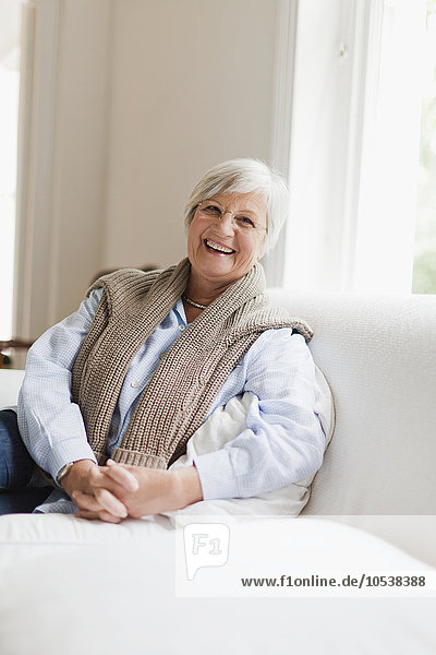 Lächelnde ältere Frau auf der Couch sitzend