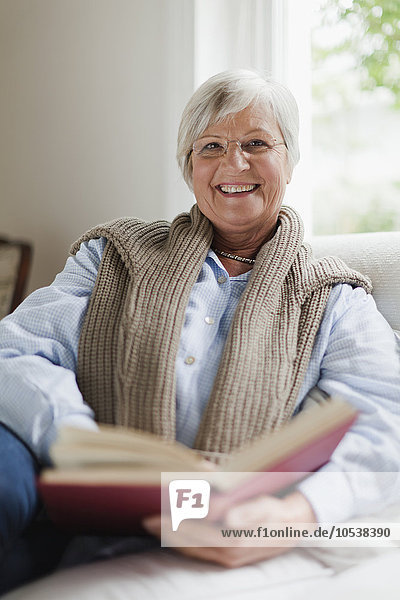 Lächelnde ältere Frau liest Buch