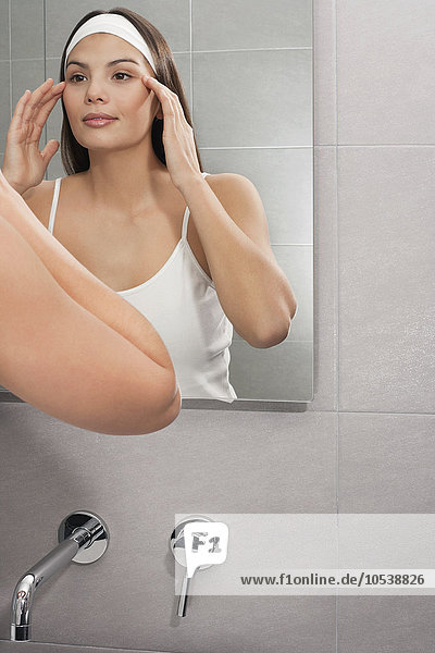 Frau untersucht ihr Gesicht im Spiegel