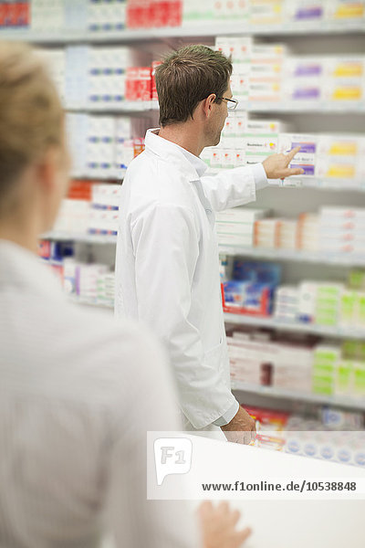 Pharmacist browsing medicines on shelf