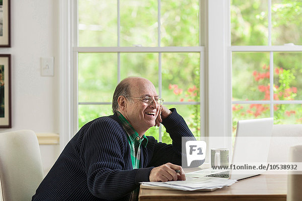 Senior Mann mit Laptop zu Hause  lächelnd