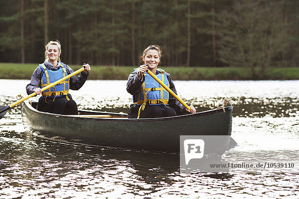 Frauen rudern Kanu auf stillem See