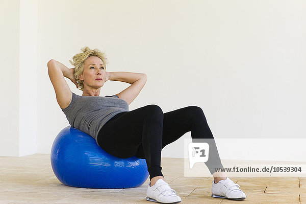 Reife Frau beim Sit-ups auf dem Fitnessball