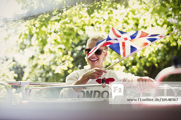Lächelnde Frau mit britischer Flagge im Doppeldeckerbus