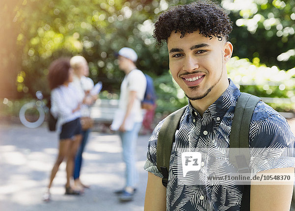 Portrait lächelnder Mann mit lockigen schwarzen Haaren im Park