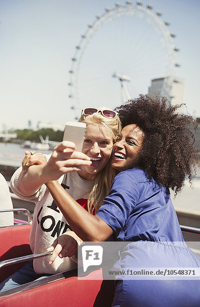 Enthusiastische Freunde im Doppeldeckerbus mit London Eye im Hintergrund