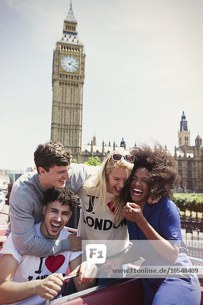 Enthusiastische Freunde im Doppeldeckerbus unter dem Big Ben-Uhrturm, London, Großbritannien