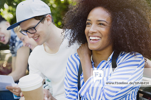 Lächelnde Frau mit Afro-Kaffee trinken mit Freunden im Freien