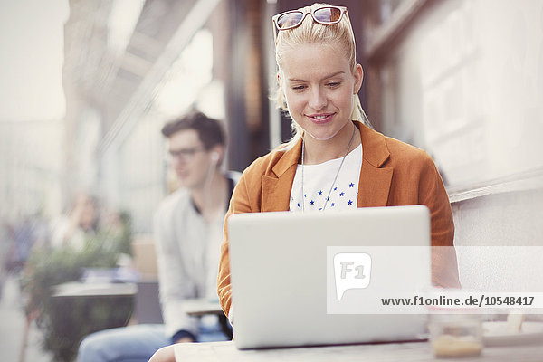 Frau mit Laptop auf dem Bürgersteig Cafe