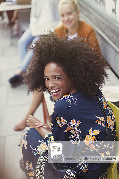 Portrait begeisterte Frau mit Afro im Straßencafé
