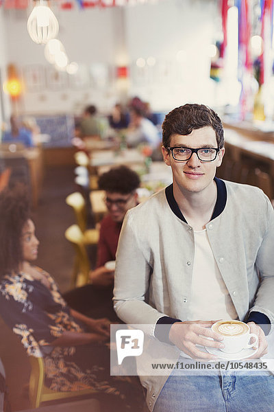 Portrait lächelnder Mann mit Brille trinkt Cappuccino im Cafe