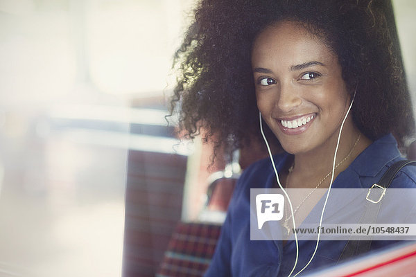 Lächelnde Frau mit Afro Musik hören mit Kopfhörer im Bus