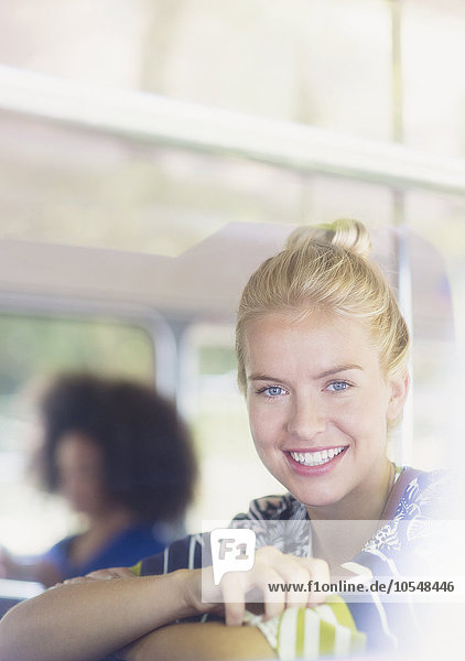 Portrait lächelnde blonde Frau mit Handy im Bus