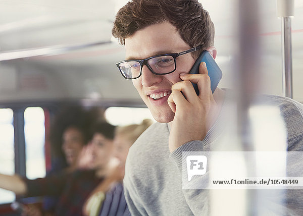Lächelnder Mann mit Brille spricht auf dem Handy im Bus