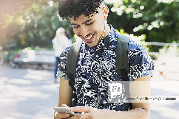 Smiling man with curly black hair listening to music with headphones and mp3 player