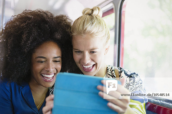 Enthusiastic friends taking selfie with digital tablet on bus
