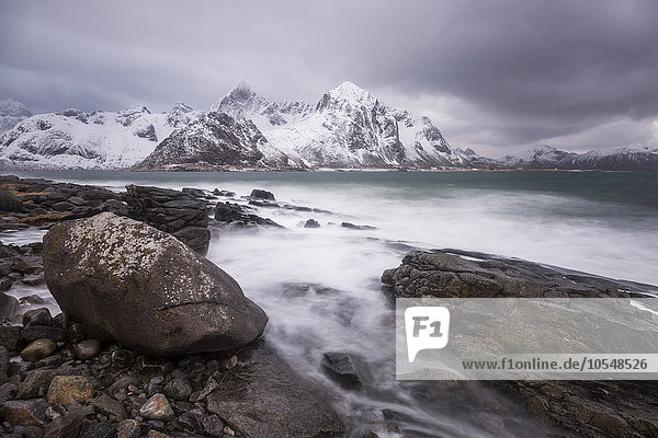 Schneebedeckte Berge hinter zerklüftetem kalten See Haukland Lofoten Inseln Norwegen