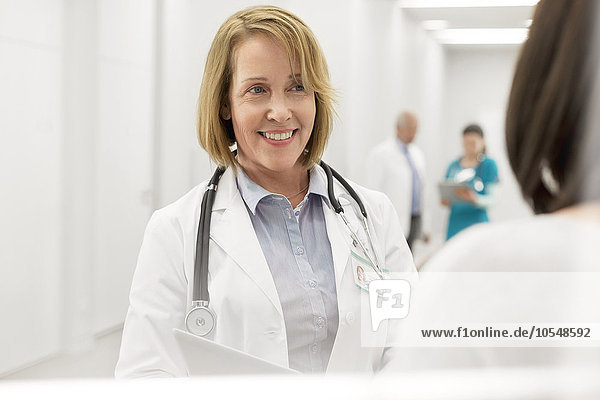 Lächelnder Arzt im Gespräch mit dem Patienten im Krankenhauskorridor