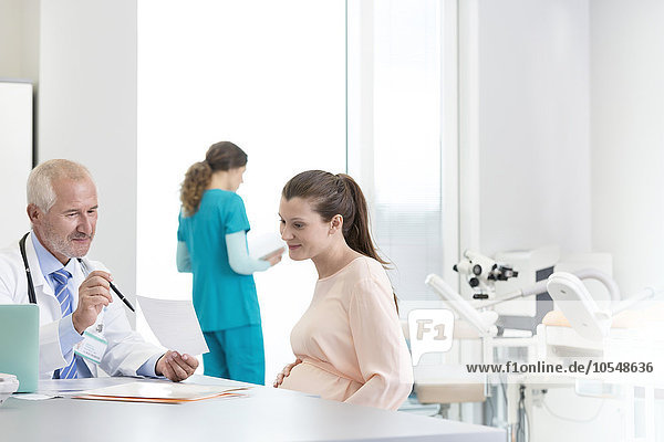 Arzt und schwangere Patientin besprechen die Verschreibung in der Klinik