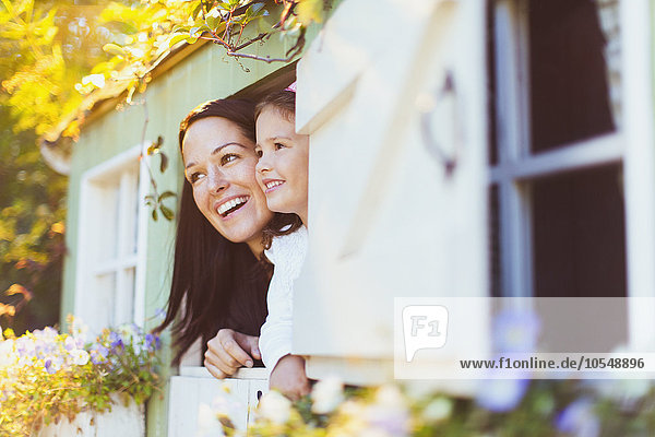 Lächelnde Mutter und Tochter im Spielhausfenster