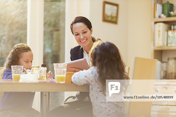 Arbeitende Mutter und Töchter am Frühstückstisch