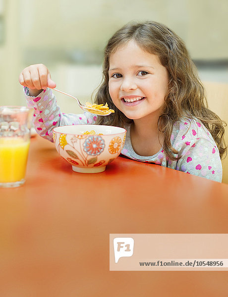 Portrait lächelndes Mädchen isst Müsli am Frühstückstisch