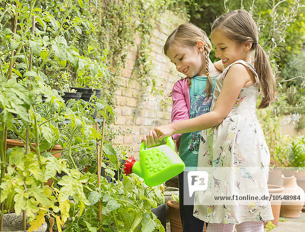 Umarmung von Mädchen beim Gießen von Pflanzen im Garten