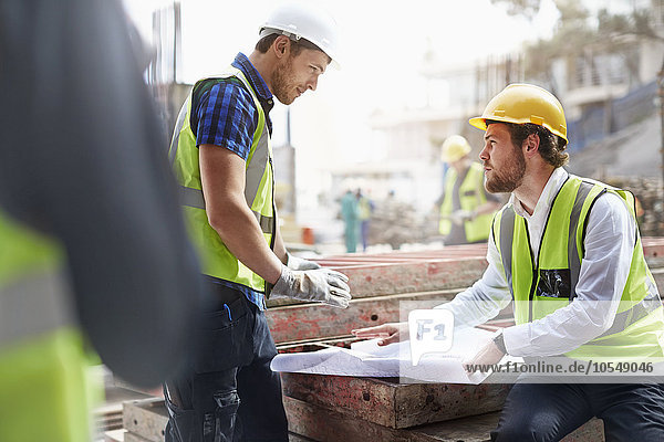 Construction worker and engineer reviewing blueprints at construction site