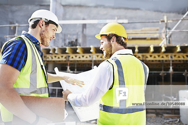 Bauarbeiter und Ingenieur bei der Begutachtung von Bauplänen auf der Baustelle