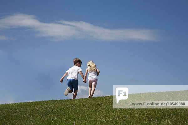 Zwei Kinder rennen auf einen Hügel