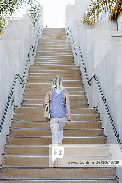 Blonde Frau geht eine Treppe hinauf.