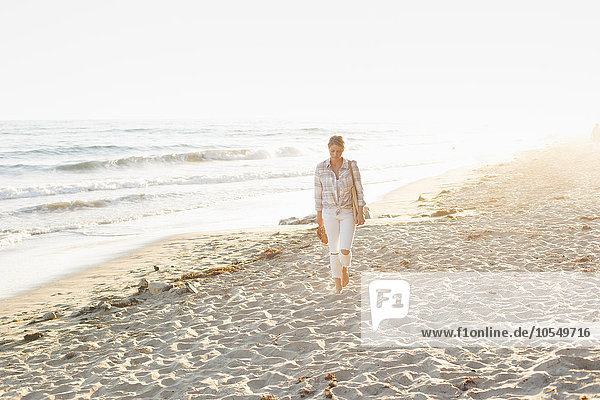 Woman walking along a sandy beach by the ocean.