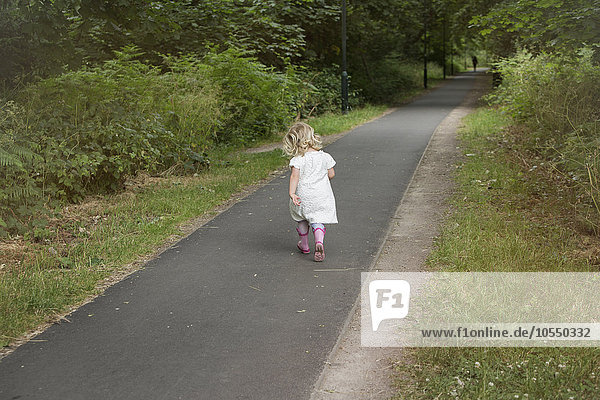 Junges Mädchen  das einen Pfad in einem Park entlangläuft.